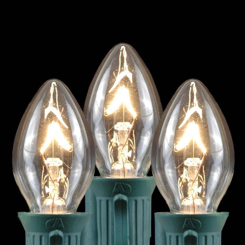 Clear Christmas bulb detail Three clear Christmas light bulbs with green sockets on a dark background.